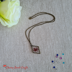Bronze resin diamond shaped pendant with red flower setting