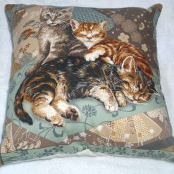 Three pretty sleepy kitties curled up on a bed cushion