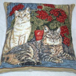 A ginger cat and tabby cat sitting in the window with pots of geraniums cushion