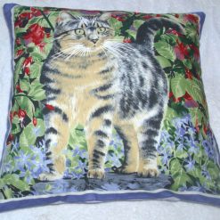 Lovely grey Tabby cat by a red fuchsia bush in the garden cushion pillow