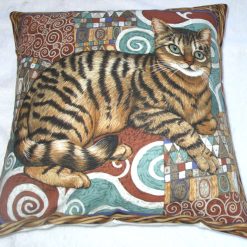 Tabby cat sitting on a mosaic patterned rug in a wicker basket cushion