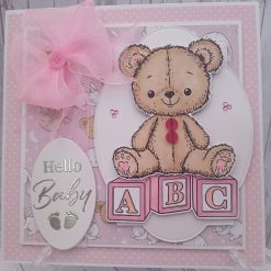 Hello Baby - Teddy bear perched on three pastel pink alphabet blocks