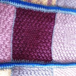 Hand knitted baby blanket in a blue and purple colourway