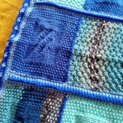 Handmade knitted baby blanket in a blue colourway.